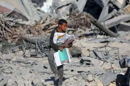 Seorang siswa Palestina di Jalur Gaza mengais buku dari sekolah yang hancur